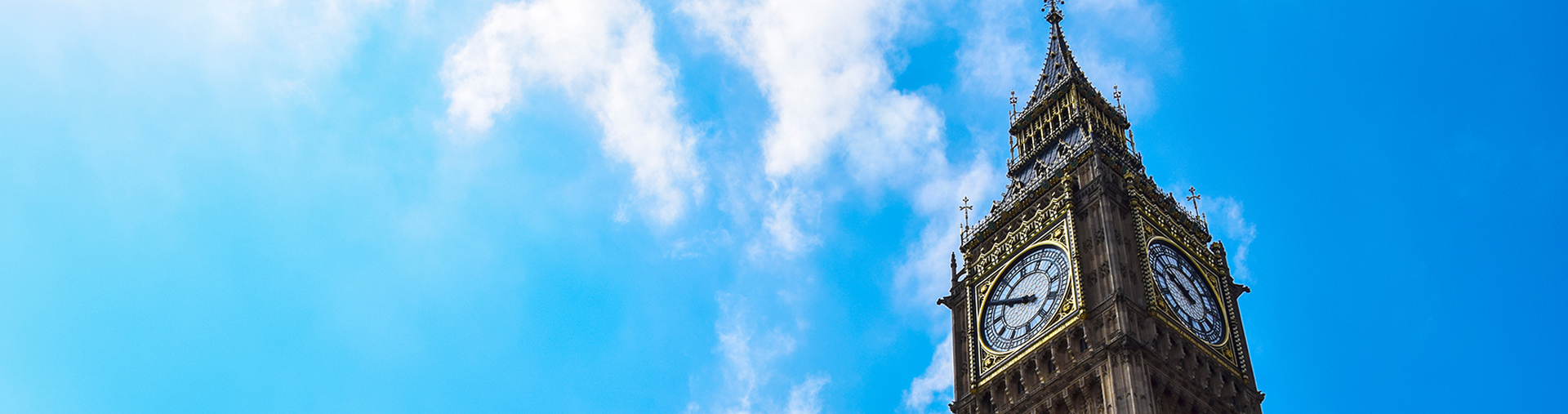 Low angle view of London’s Big Ben against a bright, cloudy blue sky