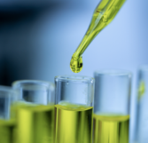 Closeup of a female scientist in a laboratory working with CBD oil extracted from a marijuana plant. She is tearing the CBD oil from one tube into another. (Source: Getty Images)