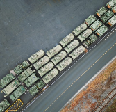 Armed military personnel carriers await shipping from an industrial dock. (source: Getty Images)